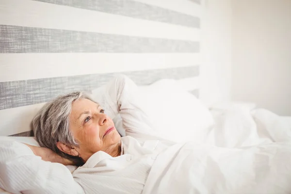 Tankeväckande senior kvinna avkopplande på sängen — Stockfoto