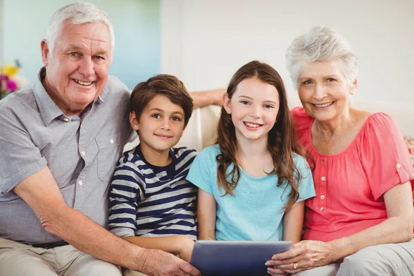 Couple using tablet with grand children — Stock Photo, Image