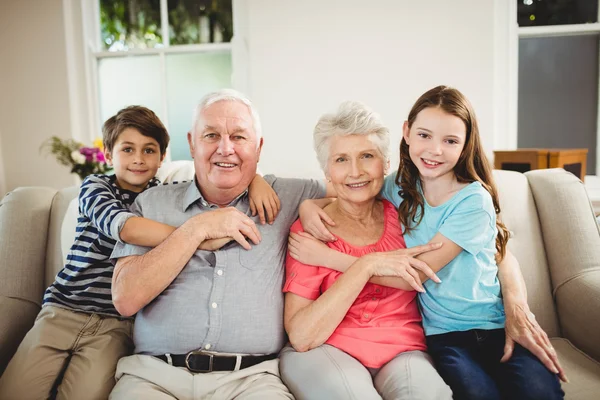 Grandparents and grandchildren sitting on sofa — Stock Photo, Image