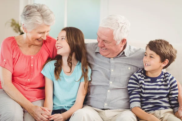 Grandparents and grandchildren sitting on sofa — Stock Photo, Image