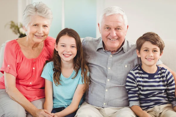 Grandparents and grandchildren sitting on sofa — Stock Photo, Image