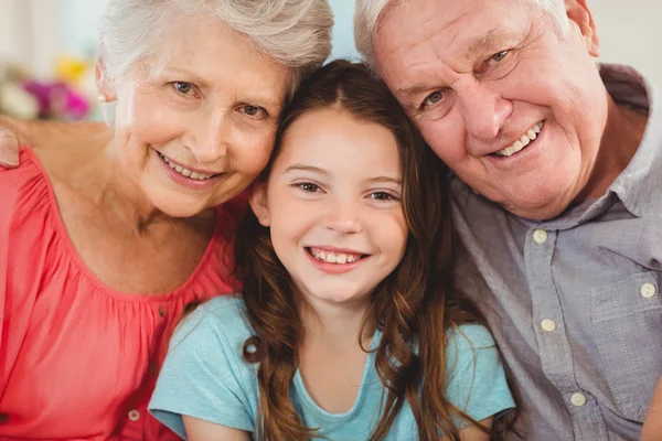 Grandparents and granddaughter sitting on sofa — Stock Photo, Image