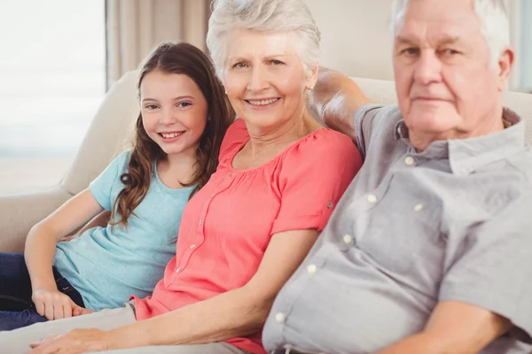 Grandparents and granddaughter sitting on sofa — Stock Photo, Image