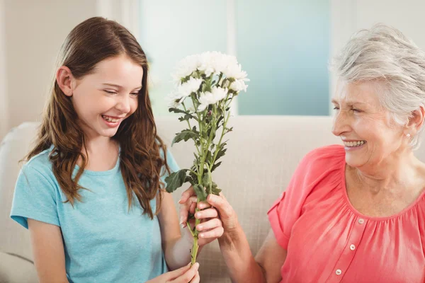 Grandmother giving flowers to granddaughter — Stock Photo, Image