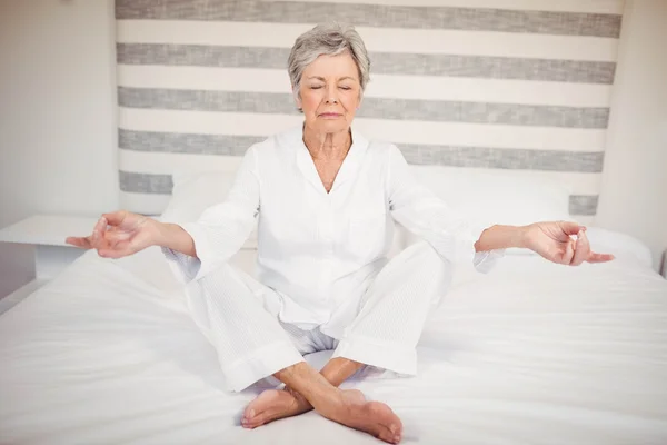 Mujer mayor meditando en la cama — Foto de Stock