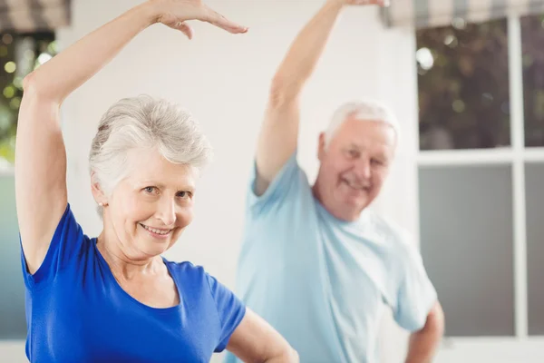 Casal sênior realizando exercício de alongamento — Fotografia de Stock