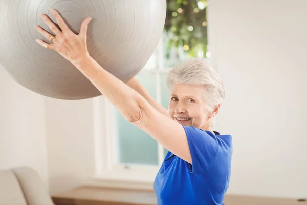 Äldre kvinna lyftande öva boll — Stockfoto