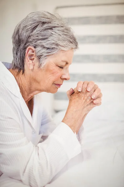 Besorgte Seniorin sitzt auf Bett — Stockfoto