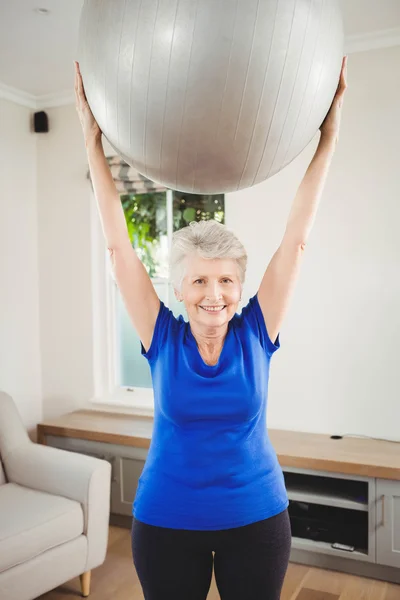 Äldre kvinna lyftande öva boll — Stockfoto