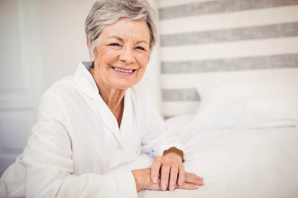 Starszy kobieta siedzi na łóżku — Zdjęcie stockowe
