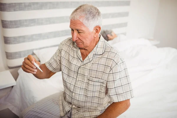 Senior hält Thermometer in der Hand — Stockfoto