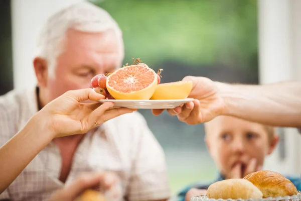 Mãos que passam prato de frutos — Fotografia de Stock