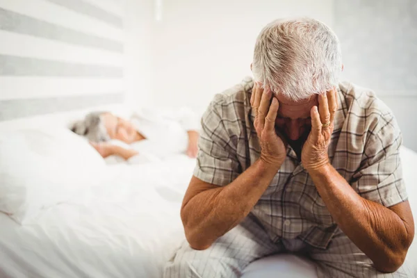 Gefrustreerd senior man zittend op bed — Stockfoto