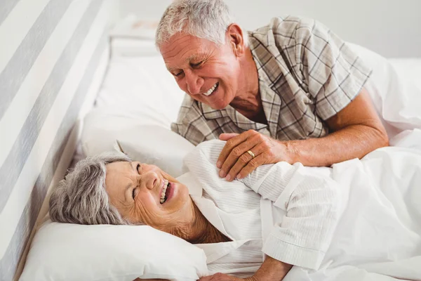 Pareja de ancianos riendo en la cama — Foto de Stock