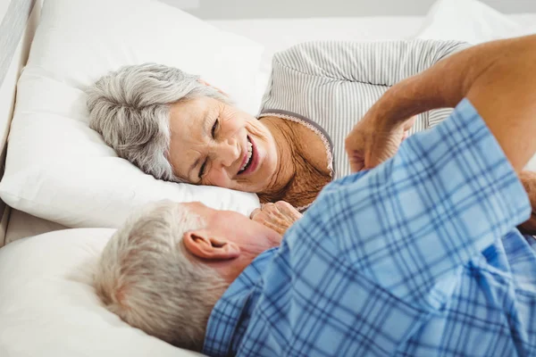 Счастливая пожилая пара улыбается в постели — стоковое фото