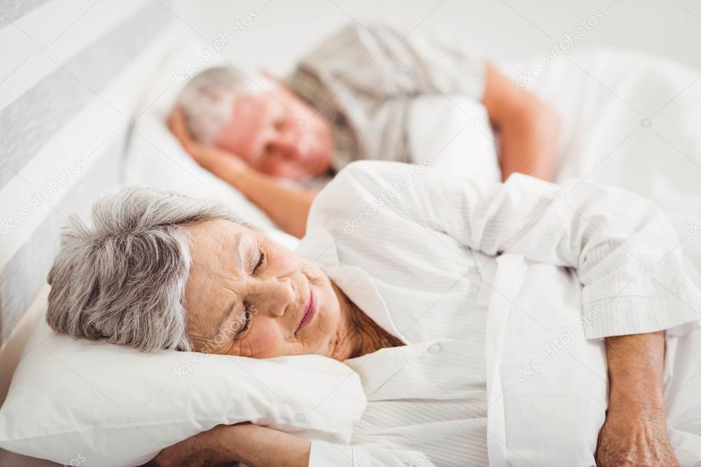 Senior couple sleeping on bed Stock Photo by ©Wavebreakmedia 100690570