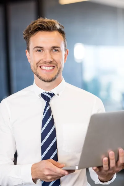 Empresário de pé com laptop no escritório — Fotografia de Stock