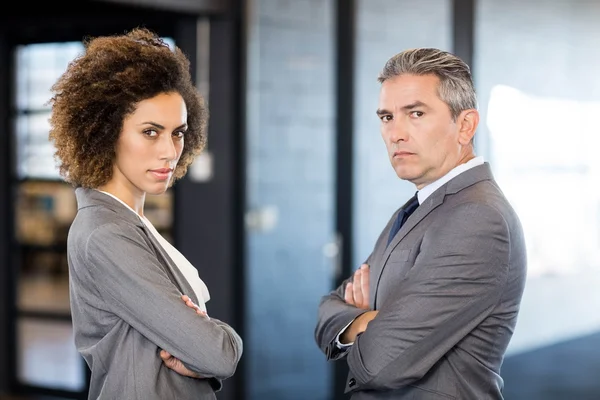 Businessman and businesswoman with arms crossed — Stock Photo, Image