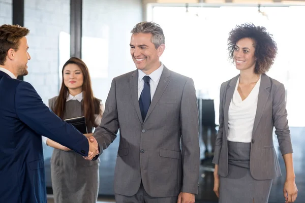 Businessman shaking hands with team — Stock Photo, Image