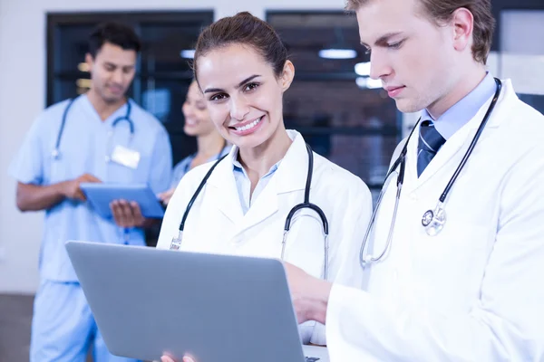 Médicos que utilizan el ordenador portátil y sonriendo — Foto de Stock