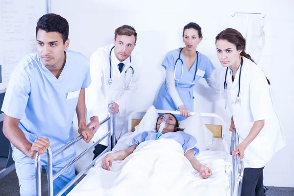 Врачи стоят рядом с пациентом на кровати — стоковое фото