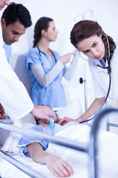 Ärzte untersuchen einen Patienten im Bett — Stockfoto