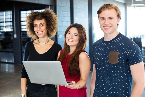 Colleghi che tengono il computer portatile e sorridono — Foto Stock