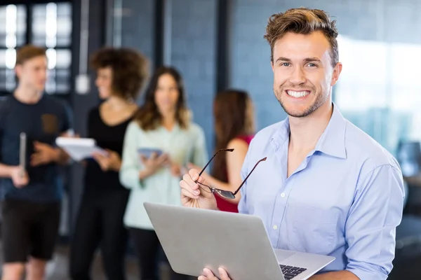 Homem segurando laptop e sorrindo — Fotografia de Stock