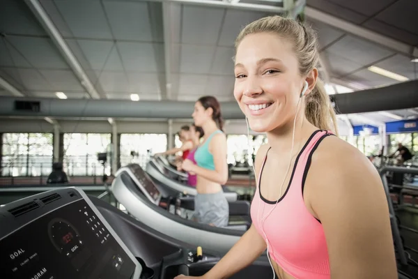 Fit woman running on the treadmill while listening music — Stock Photo, Image