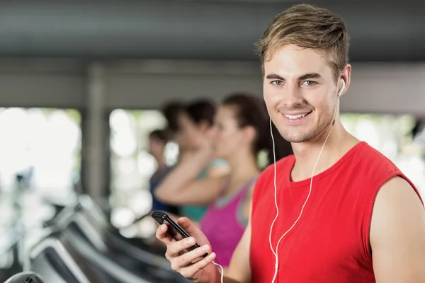 Sonriente hombre musculoso en la cinta de correr escuchando música — Foto de Stock