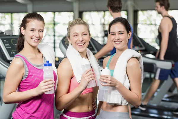 Sportovní usmívající se ženy představují s lahví vody — Stock fotografie
