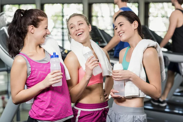 Atlético sorrindo mulheres posando com garrafa de água — Fotografia de Stock
