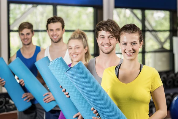 Pessoas com tapete de fitness no ginásio — Fotografia de Stock