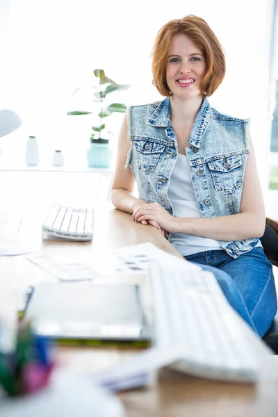 Mujer hipster sonriente sentada en el escritorio — Foto de Stock
