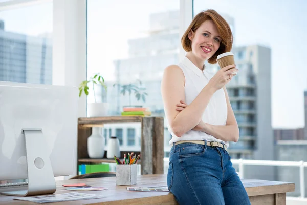 Geschäftsfrau lehnt am Schreibtisch und trinkt Kaffee — Stockfoto