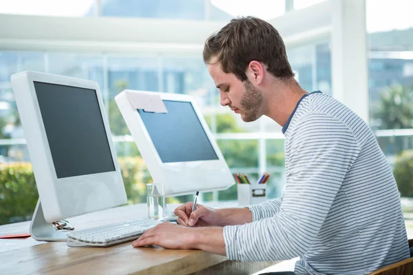 Man working on computer and taking notes — Stock Photo, Image