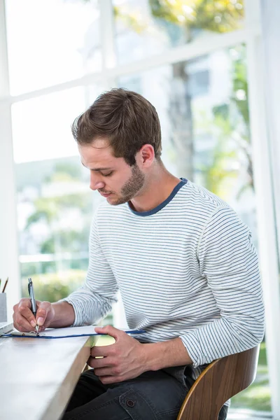 Knappe man het maken van notities op Klembord — Stockfoto