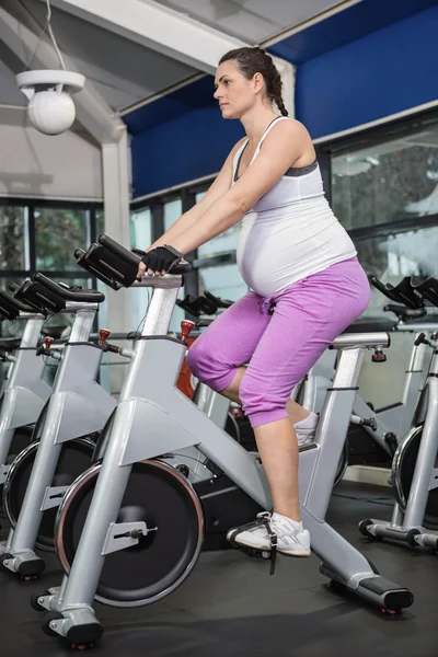 Hamile kadın egzersiz bisikleti kullanarak — Stok fotoğraf