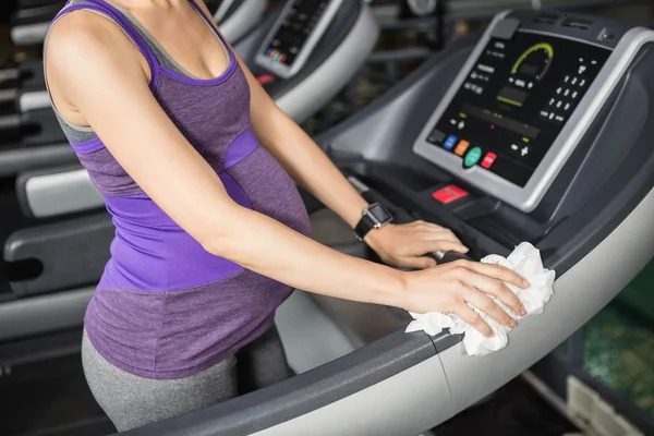 Pregnant woman cleaning treadmill — Stock Photo, Image