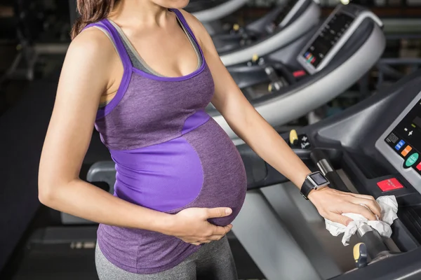 Pregnant woman cleaning treadmill — Stock Photo, Image