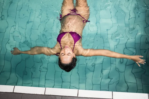 Mujer embarazada flotando en la piscina — Foto de Stock