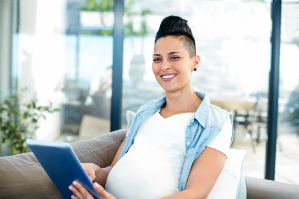 Беременная женщина на диване с планшетом — стоковое фото