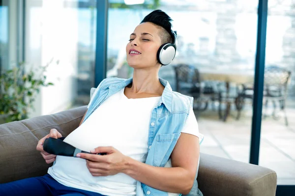 Mulher grávida ouvindo música no sofá — Fotografia de Stock