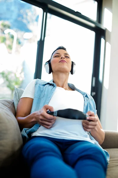 Hamile kadın kanepe üzerinde müzik dinleme — Stok fotoğraf