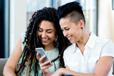 Lesbian couple looking at mobile phone clipart