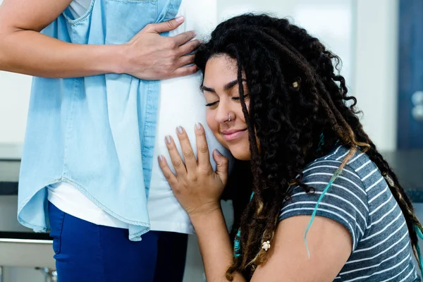 Женщина слушает беременных партнеров желудок — стоковое фото