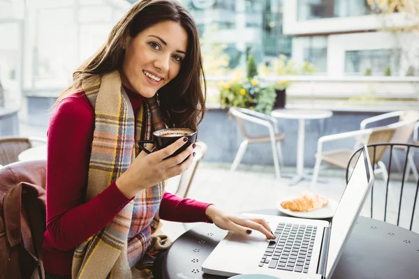Woman using laptop drinking coffee — Stock Photo, Image