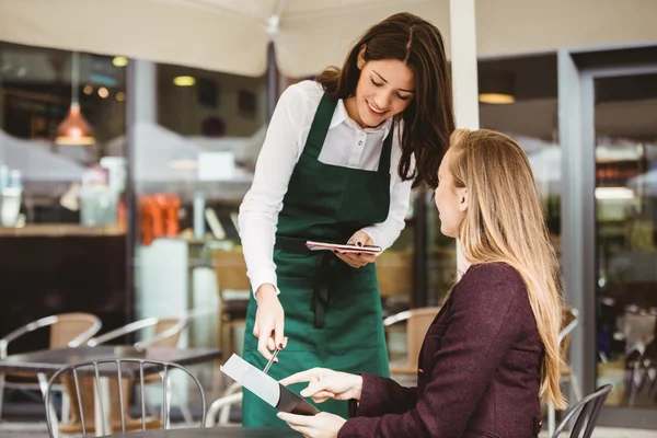 Lächelnde Kellnerin, die eine Bestellung entgegennimmt — Stockfoto