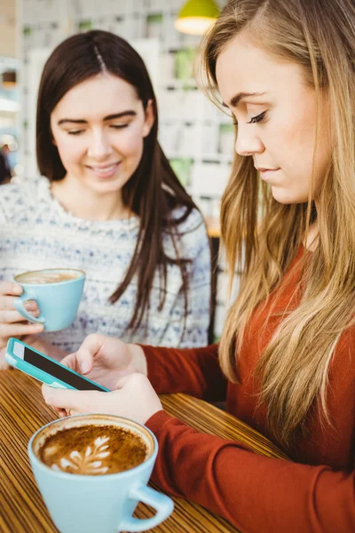 Друзья используют смартфон и пьют кофе — стоковое фото