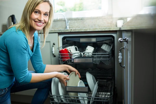 Vrouw leegmaken vaatwasser Stockafbeelding